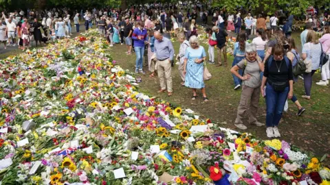 PA Media Members of the public view floral tributes in Green Park, near Buckingham Palace