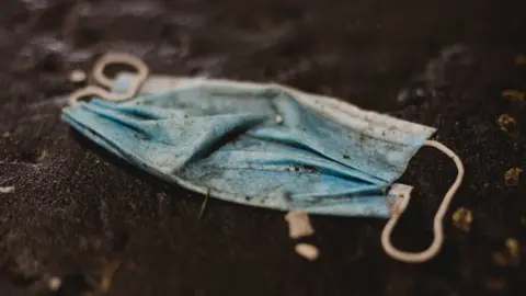 Getty Images Dirty disposed face mask lying in dirt