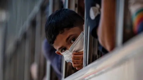 Getty Images A boy wearing a facemask peers out from the window of a bus about to leave Manila before it is placed on lockdown on March 13, 2020 in Quezon city, Metro Manila, Philippines.