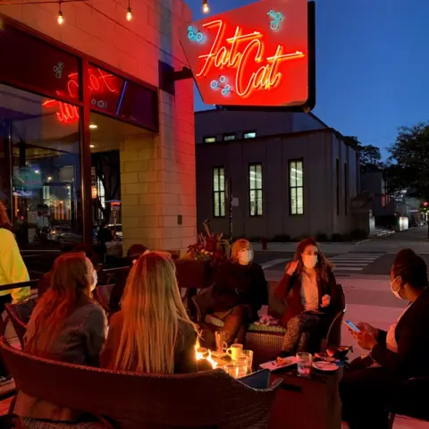 Cy Oldham People sit outside at a table at Fat Cat bar in Chicago