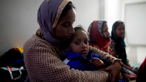 Getty Images A woman holds her daughter at Al-hind Hospital where they have taken shelter with other families after losing their homes following sectarian riots over India's new citizenship law, in Delhi, 28 February
