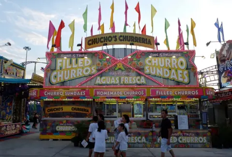 BBC A churros stand brightly decorated with lights and flags