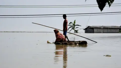 Getty Images Villagers cross a flooded area on a makeshift raft, in Panikhaiti village, in Kamrup District, Assam, India on Tuesday, on July 14, 2020.