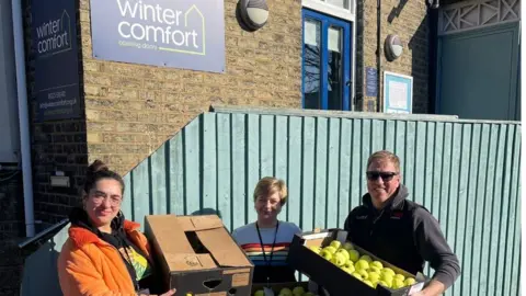 Cambridge half marathon Boxes of apples being held by people outside the charity Winter Comfort