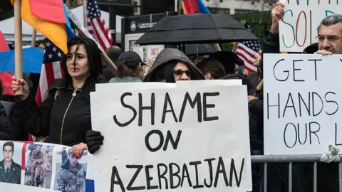 Getty Images Armenian protesters hold a sign saying Shame on Azerbaijan