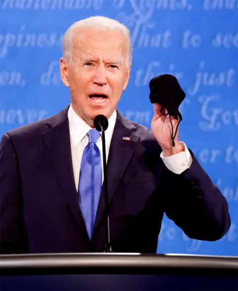 Reuters Joe Biden holds up his mask