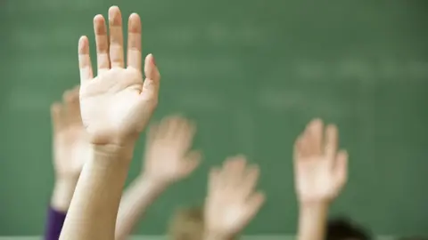 Getty Images Hands up in classroom