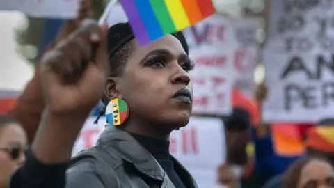 Rodger Bosch/AFP A woman in a beret holding up a rainbow flag - 24 July 2023