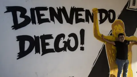 AFP A fan poses in front of a mural reading "Welcome Diego!"