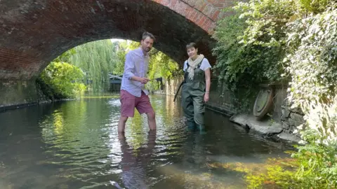 Alex Hammond Green MP Caroline Lucas standing in the River Waveney in Suffolk