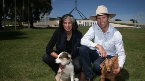 Farmers for Climate Action A man and a woman outside Australian parliament with a dog and a mini goat