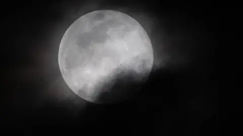 AFP The super worm moon partly covered in cloud