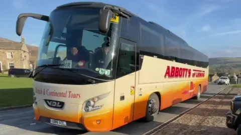 A school bus full of students arrives in Reeth