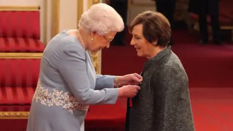 PA The Queen pinning the award to Delia Smith's coat