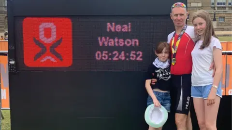 Alison Watson Neal Watson and his two daughters near the time board showing he completed the Outlaw Half Holkham in five hours, 24 minutes and 52 seconds