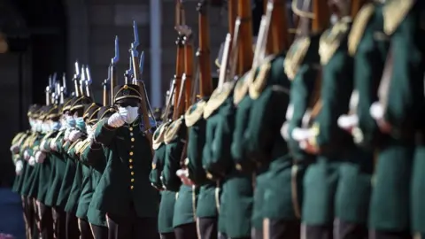 EPA The honour guard standing in line, in what appears to be a march. They are wearing a green uniform and masks.