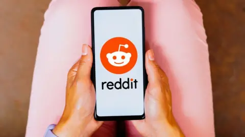 Getty Images a person looks at reddit app on a phone