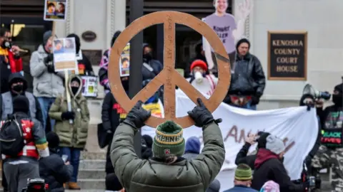 Protester outside court holds up a big peace sign