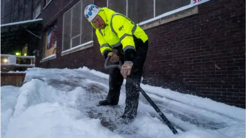 Getty Images A worker shovels snow