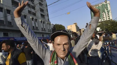 EPA A supporter of convicted former prime minister Imran Khan's Pakistan Tehrik-e-Insaf (PTI) political party wearing a mask depicting Khan takes part in a protest against alleged rigging in the general elections, outside the provincial election commission office in Karachi, Pakistan, 11 February 2024.