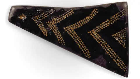 MNH A decorated jet bead before sand has been removed