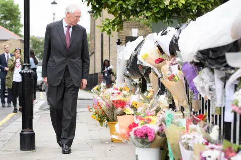 Getty Images Sir Martin Moore-Bick looks at flowers at a Grenfell tribute