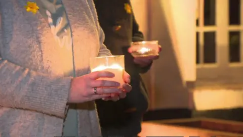 Two people holding lit candles