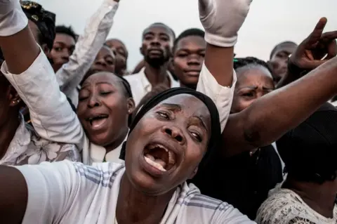AFP Supporters of late former DR Congo Prime Minister and opposition leader Etienne Tshisekedi, react as his casket passes in Kinshasa ahead of his burial on 1 June.