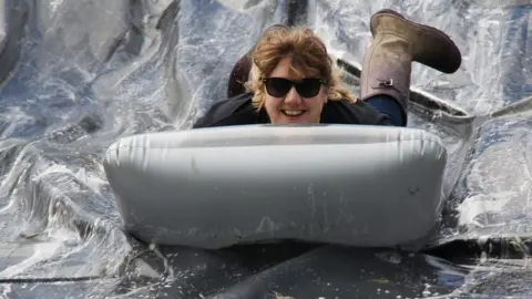 World Alternative Games Woman slides down a water slide on an inflatable mattress