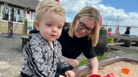 Family Handout A mum and her young son playing together with toys in a sandbox
