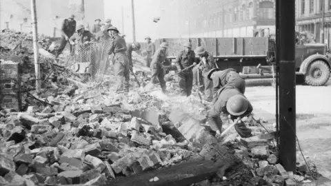 Bainbridge (Lt), War Office official photographer Royal Welch Fusiliers assist in clearing bomb damage in Belfast, Northern Ireland, 7 May 1941