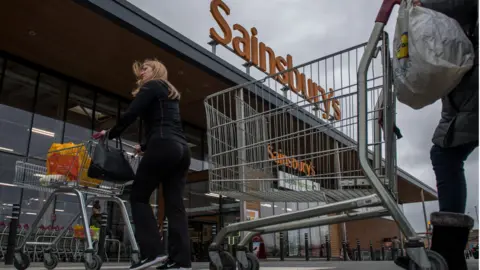 Getty Images LONDON, ENGLAND - APRIL 29: Shoppers push shopping trolleys towards a Sainsbury's supermarket on April 29, 2018 in London, England.