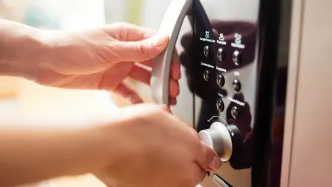 Getty Images hand on microwave