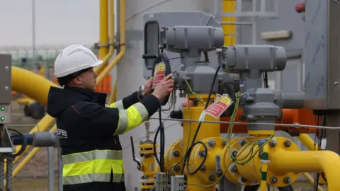 Getty Images worker of Polish natural gas company Gaz System stands among pipes at a compressor station of the new Baltic Pipe natural gas pipeline on the day of the pipeline's official opening on September 27, 2022