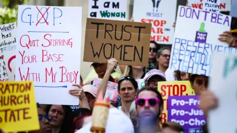 Getty Images Women hold signs during a protest against a new abortion law in Atlanta on 21 May