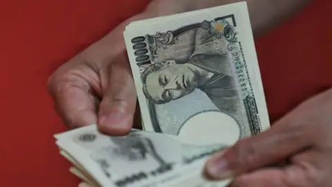 Getty Images A person counts Japanese 10,000 yen banknotes.