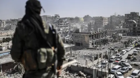 Getty Images A fighter of the Syrian Democratic Forces stands guard on a rooftop in Raqqa after retaking the city from Islamic State