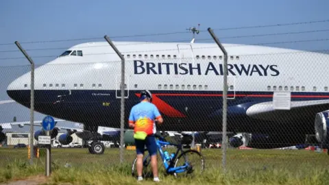 AFP A cyclist standing near a British Airways plane