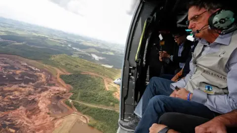 EPA Brazilian President Jair Bolsonaro (R) as he sits inside a helicopter flying over the area affected by the dam burst near Brumadinho, Minas Gerais, Brazil, 26 January 2019