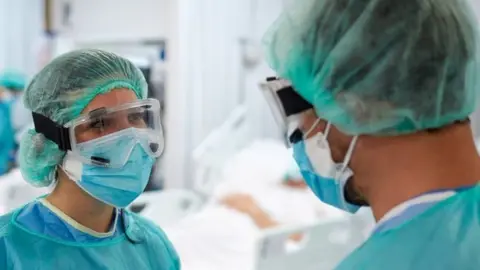 Getty Images Two people in PPE talking