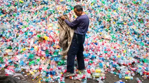 Getty Images A Chinese worker sorting out plastic bottles for recycling on the outskirts of Beijing.