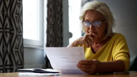 Getty Images Pensioner looking at bills