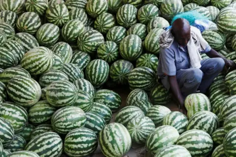 Reuters A man arranges watermelons as he waits for customers.