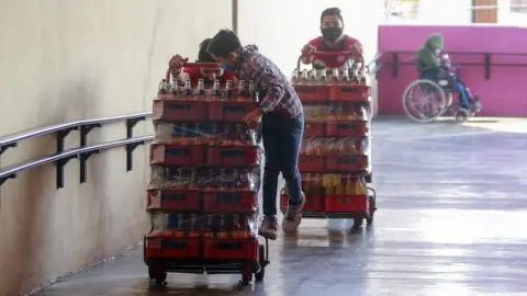 Getty Images Workers carry sodas while wearing protective masks on May 9, 2020 in Queretaro , Mexico.