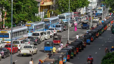 Getty Images Motorists queue along a street to buy fuel at Ceylon petroleum corporation fuel station in Colombo on May 18, 2022.