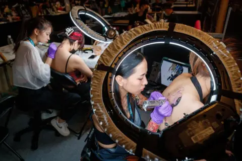 Ritchie B Tongo / EPA-EFE Tattoo artists draw designs during the Taipei Tattoo Show, Taipei, Taiwan