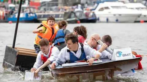 Bristol Harbourside Festival A group racing in last year's competition - they are directing a carboard boat in the harbour