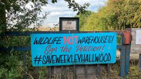 BBC "Wildlife not warehouses" attached to fence on edge of wood