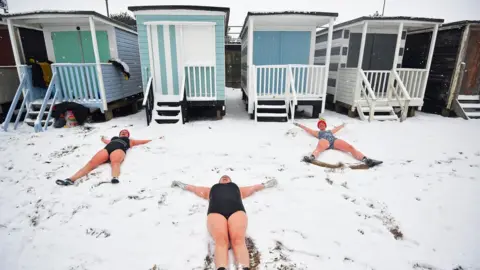 PA Media Swimmers makes angels in the snow at Thorpe Bay, Essex