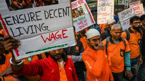 Delivery workers of Swiggy, an Indian food-delivery startup, hold placards during a demonstration demanding a hike in their remuneration, in Kolkata, on November 22, 2022. They also demanded that the company should guarantee health and accidental benefits for the delivery workers.